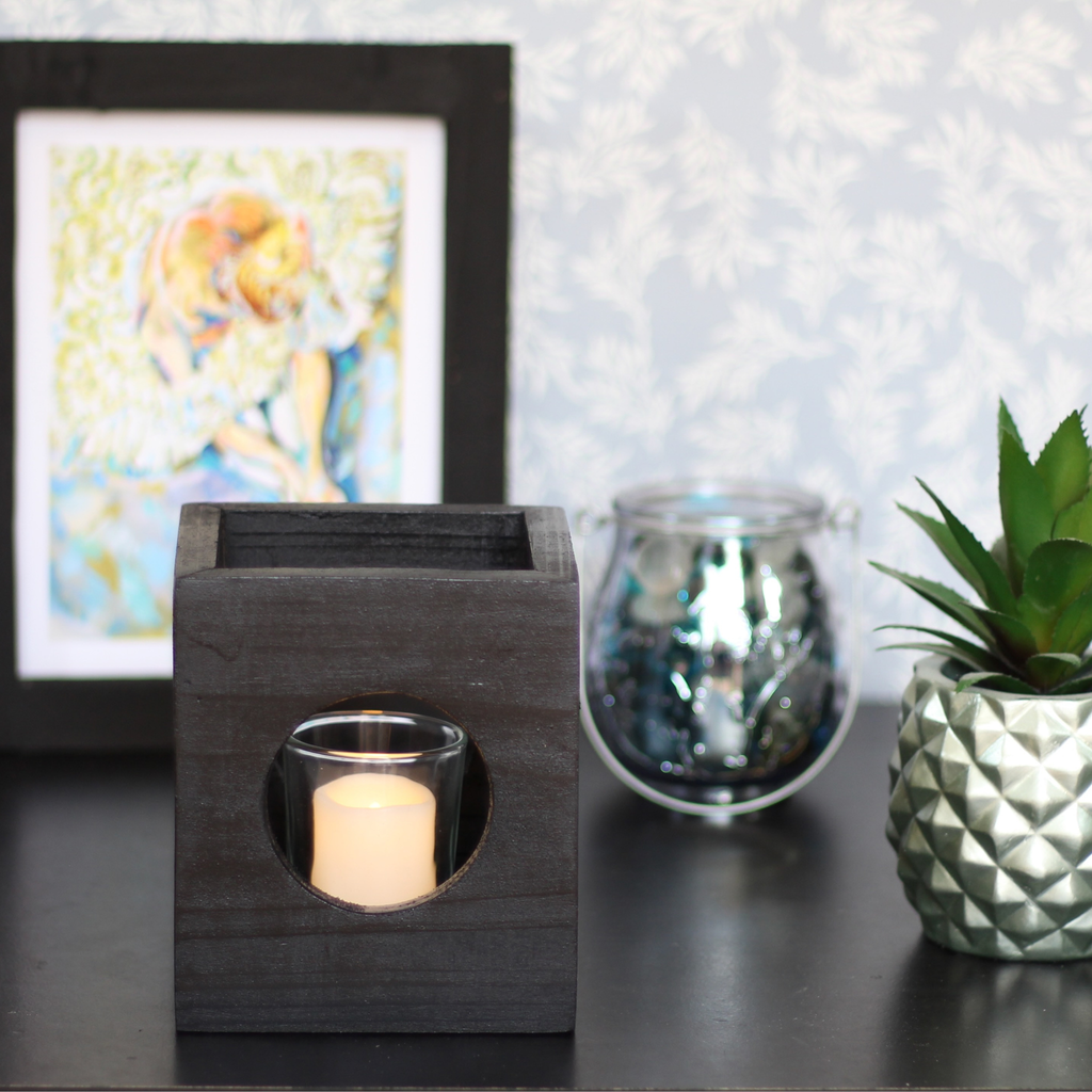 Black modern minimalist Cube-shaped wooden candle holder with circular cutouts showing glass votive holder