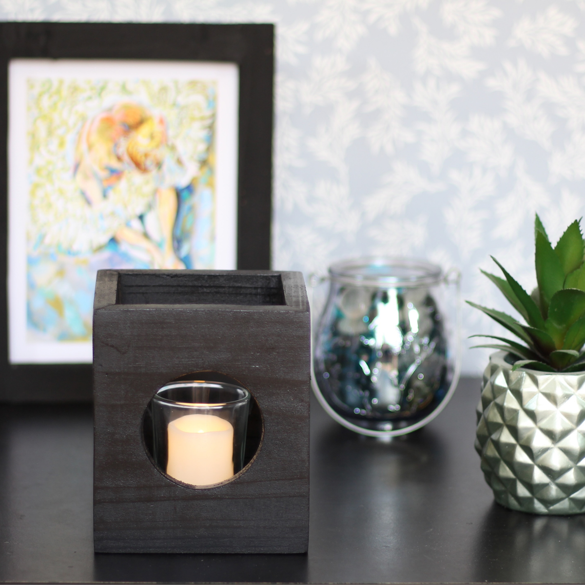 Black modern minimalist Cube-shaped wooden candle holder with circular cutouts showing glass votive holder