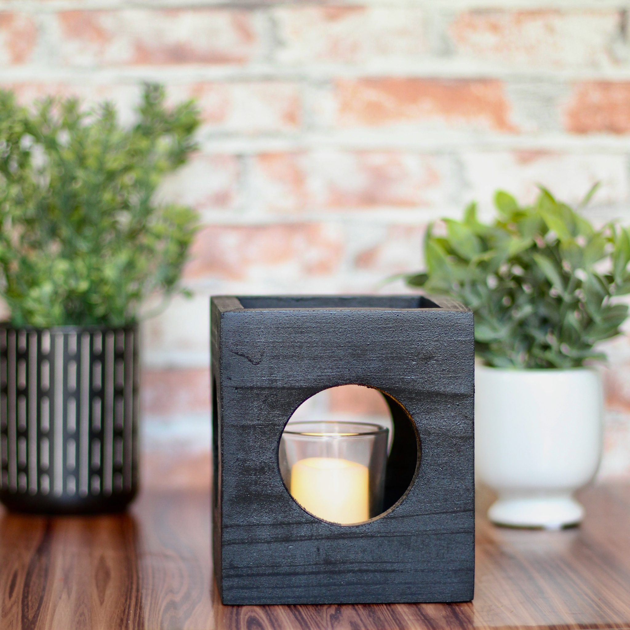Black modern minimalist Cube-shaped wooden candle holder with circular cutouts showing glass votive holder